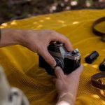 Hands adjusting vintage camera lens on wooden table
