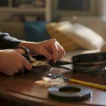 Hands splicing film reel on wooden table