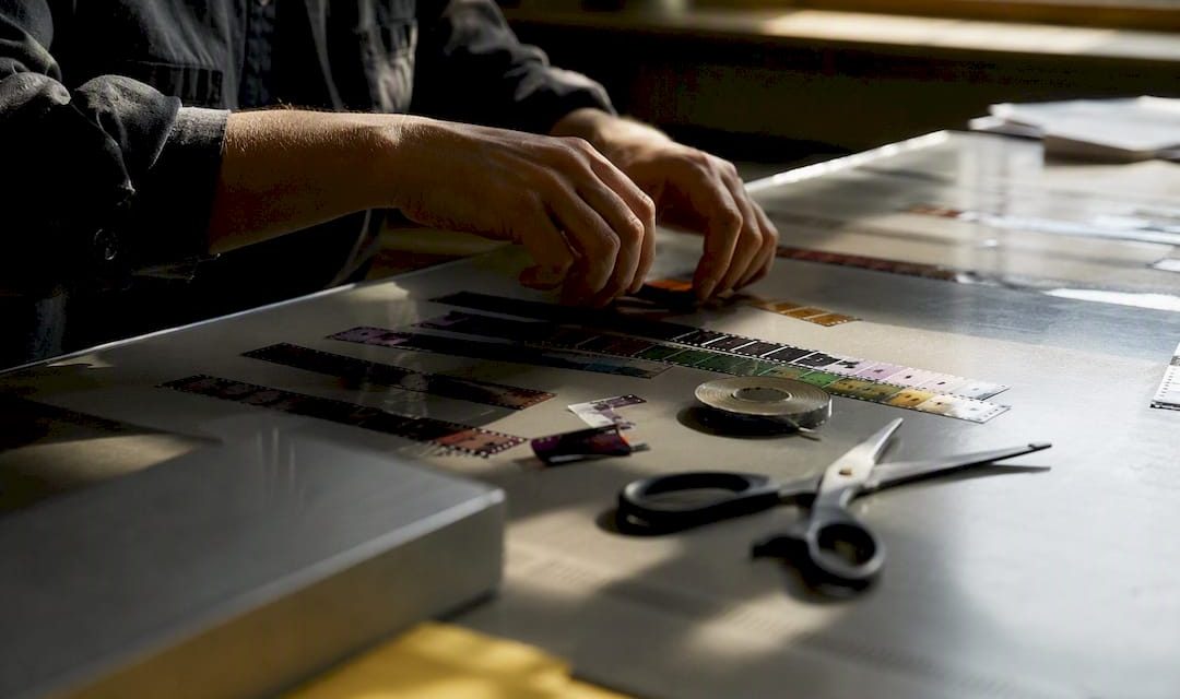 Hands splicing film strip on wooden table
