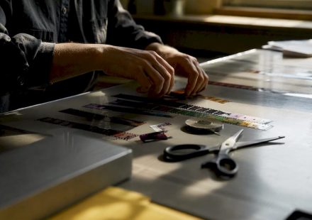 Hands splicing film strip on wooden table