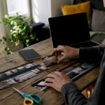 Hands editing analog film strips on wooden table