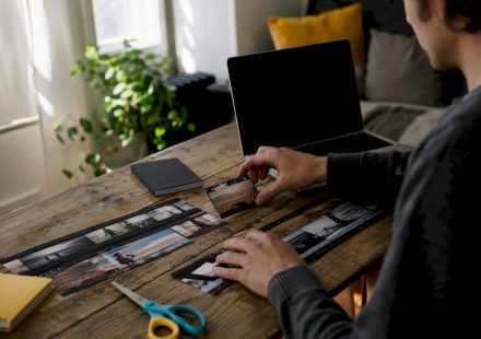 Hands editing analog film strips on wooden table