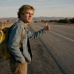 Hitchhiker standing safely beside roadside shoulder